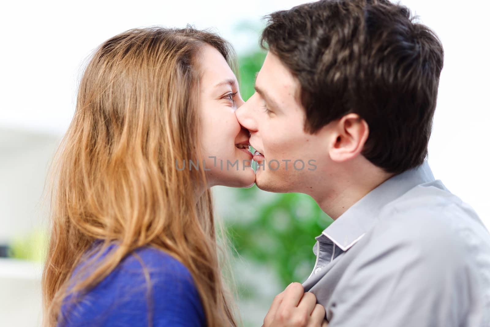 Attractive couple of lovers kissing itself lovingly on a sofa by pixinoo