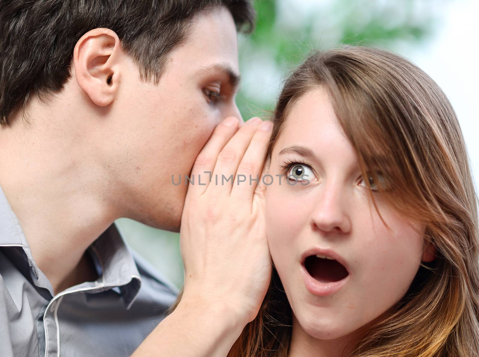 man whispering in the ear of his surprised wife