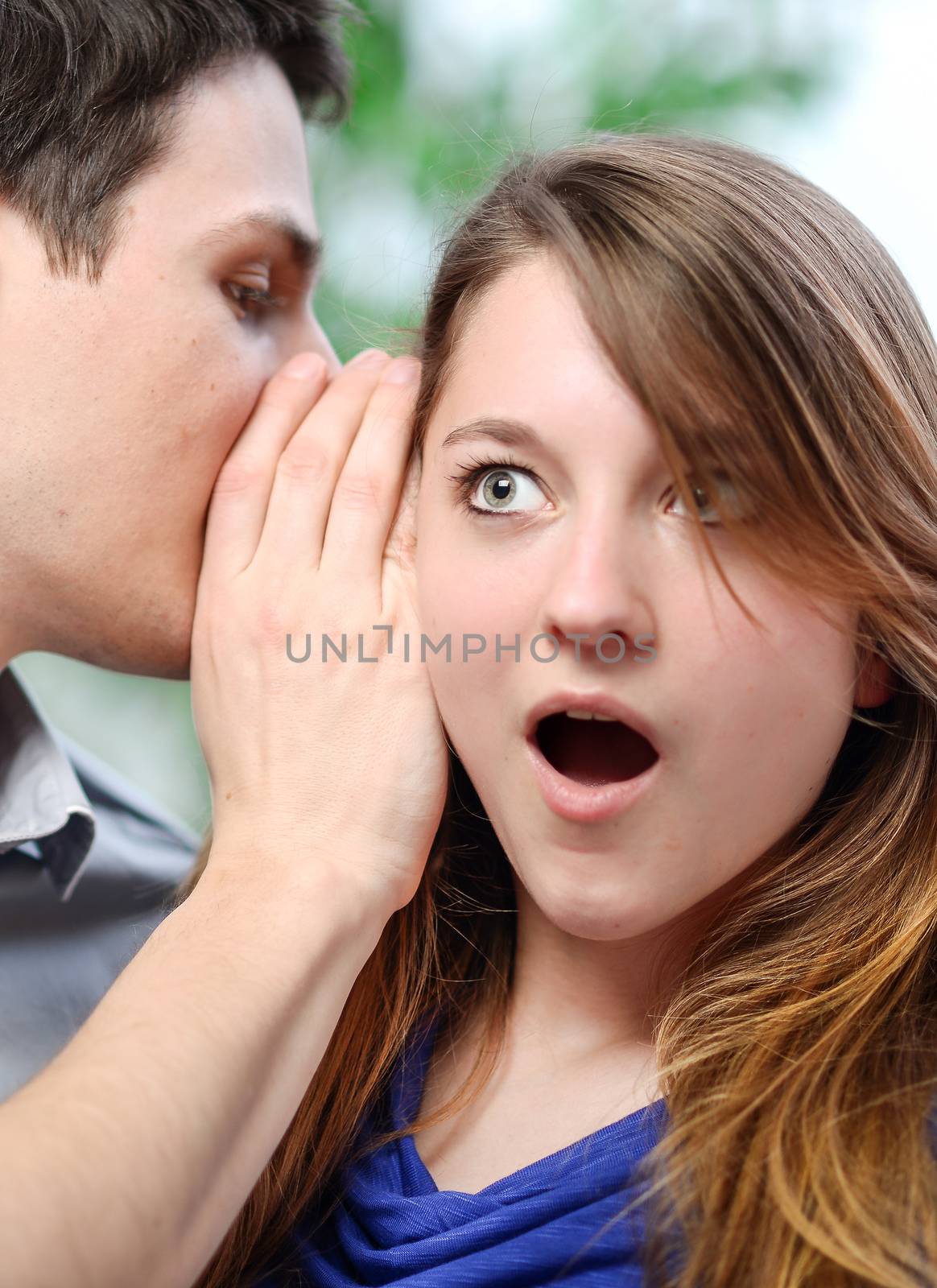 man whispering in the ear of his surprised wife