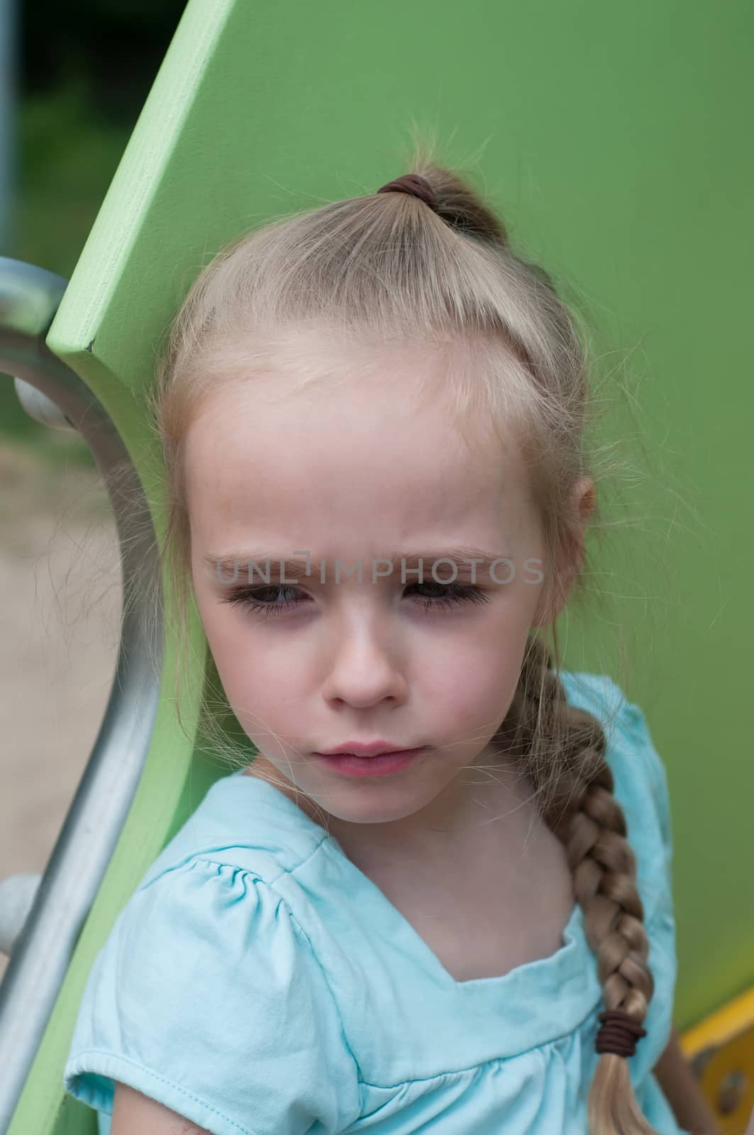 Serious young girl sitting on the playground