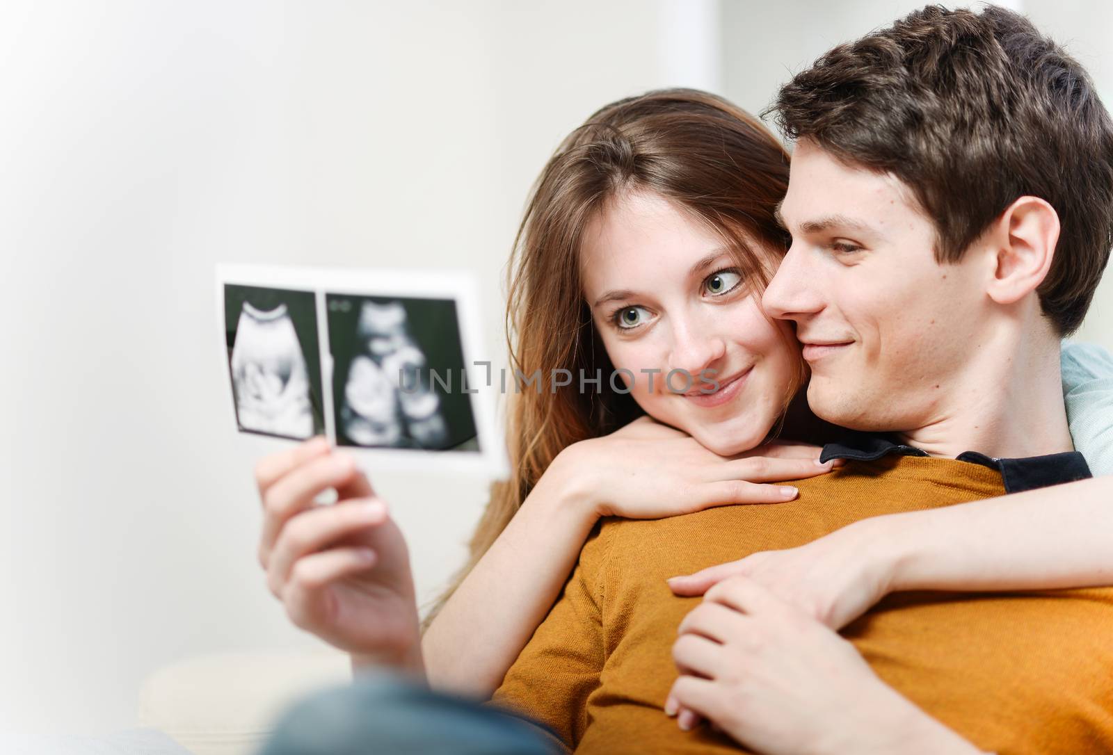 Beautiful couple watching with emotion ultrasound pictures of their baby