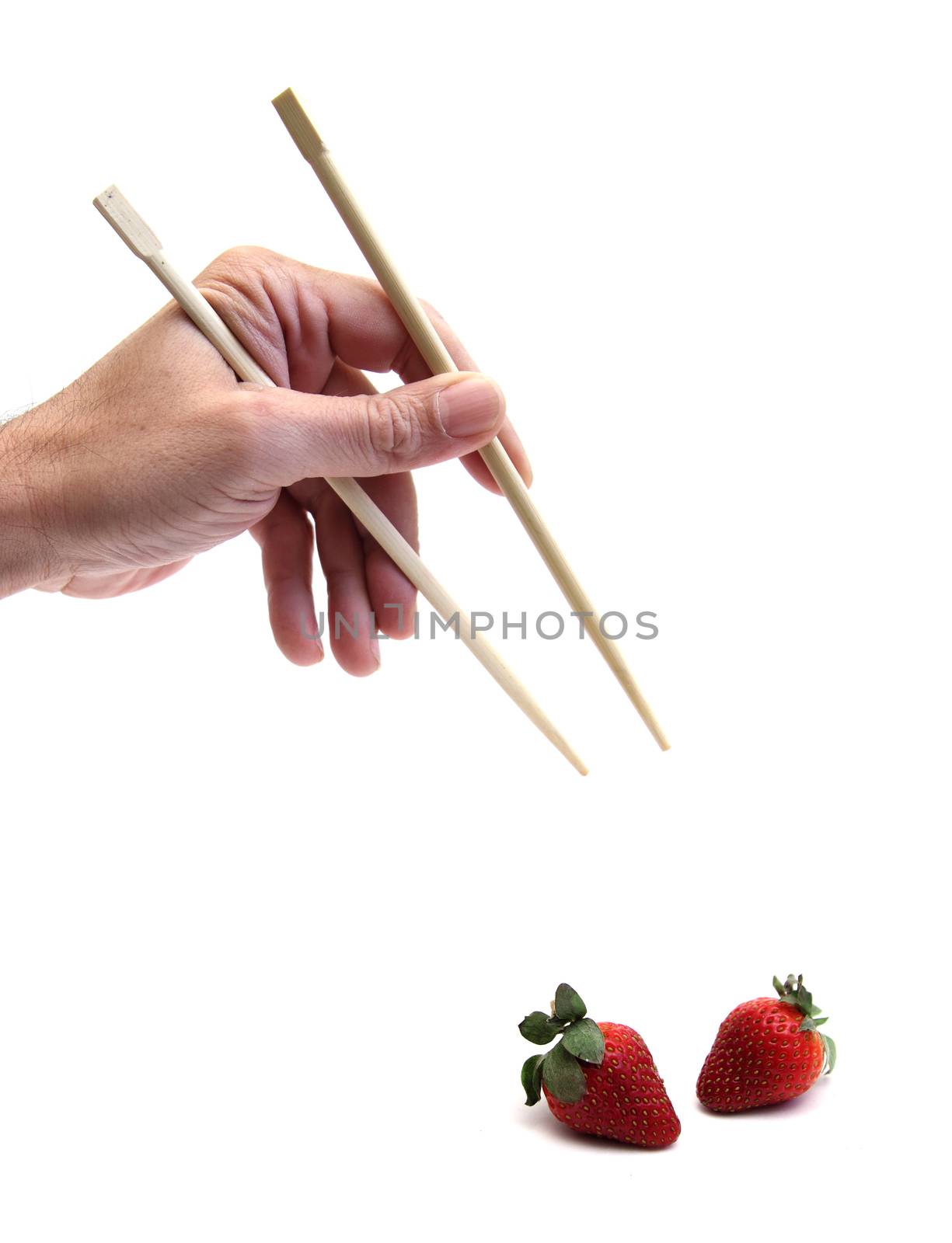 hand using chopsticks to get a strawberry over white
