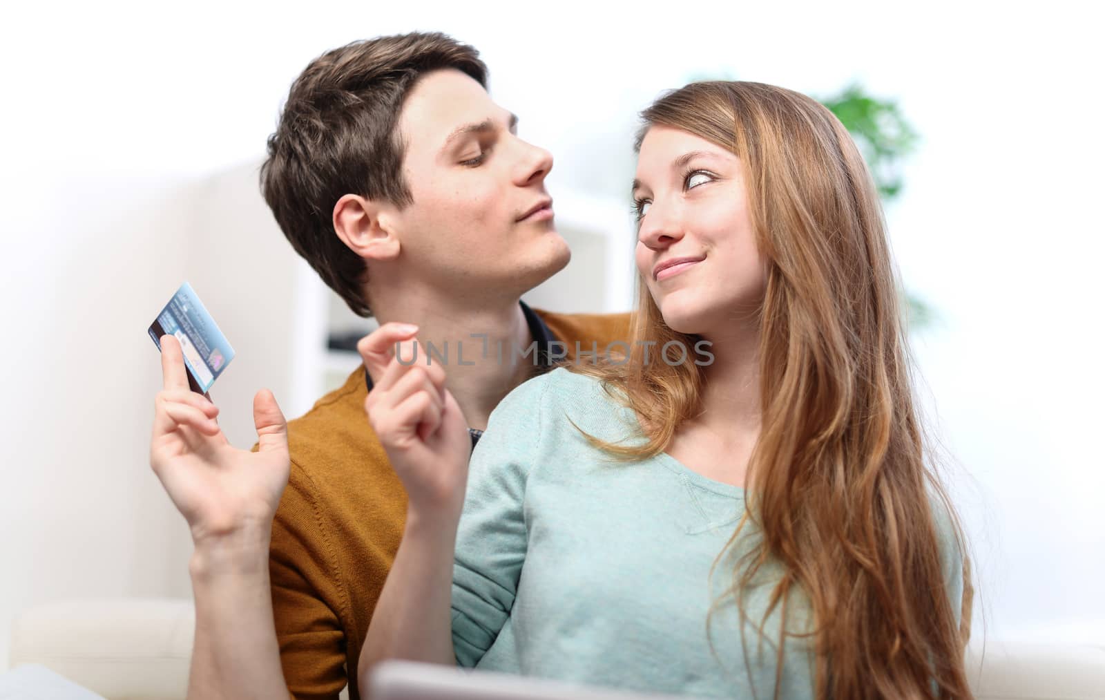 Funny smiling couple using credit card to Internet shop on-line