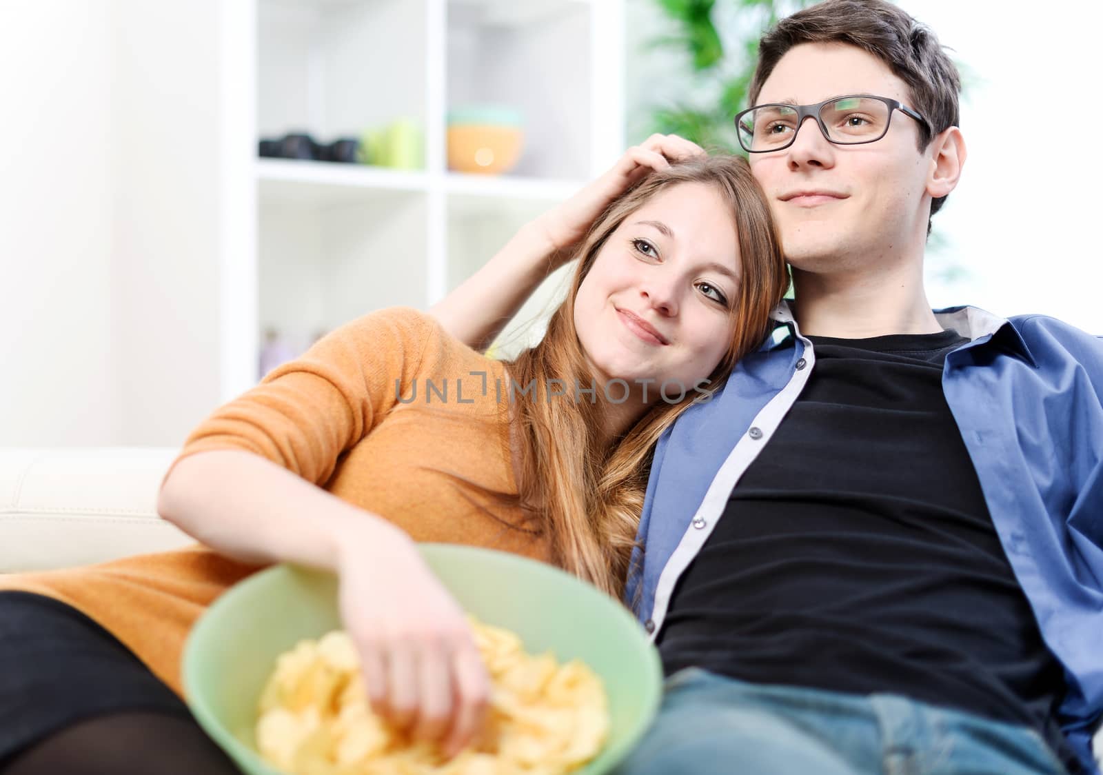 Relaxed young couple watching television in their living room by pixinoo