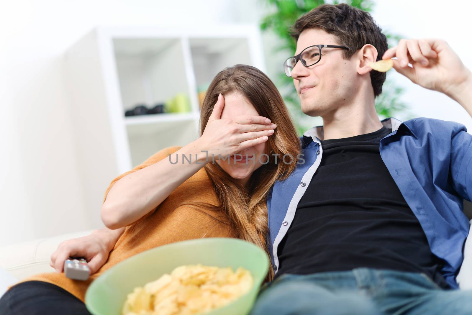 Pretty lovers eating and watching an horror movie