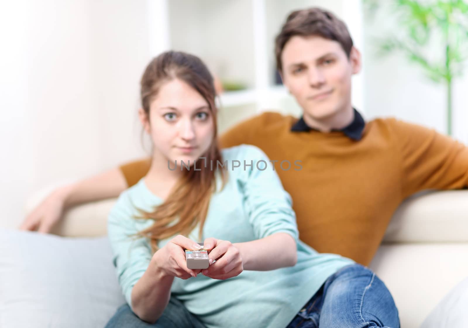 Couple sitting in sofa with remote control in hands