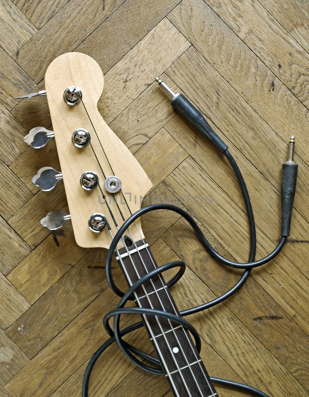 electric bass and audio cable on wood background