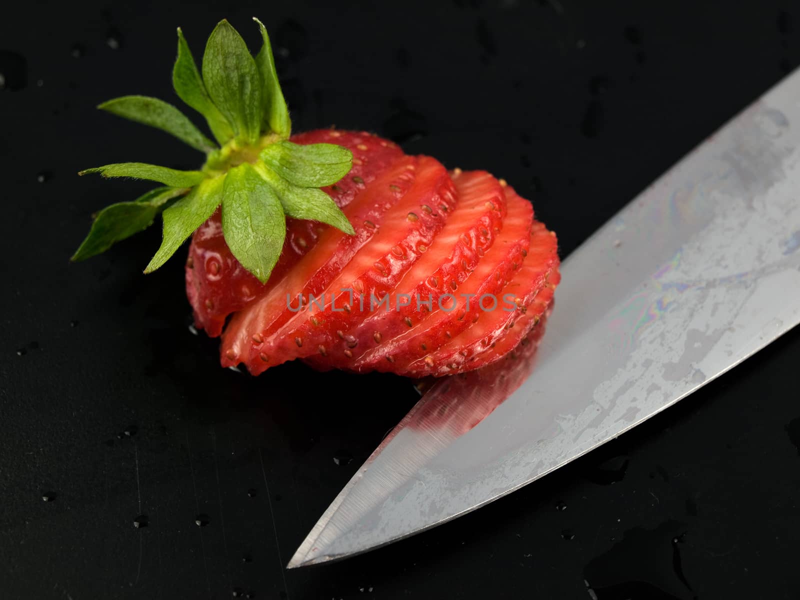 sliced srawberry with kife on black
