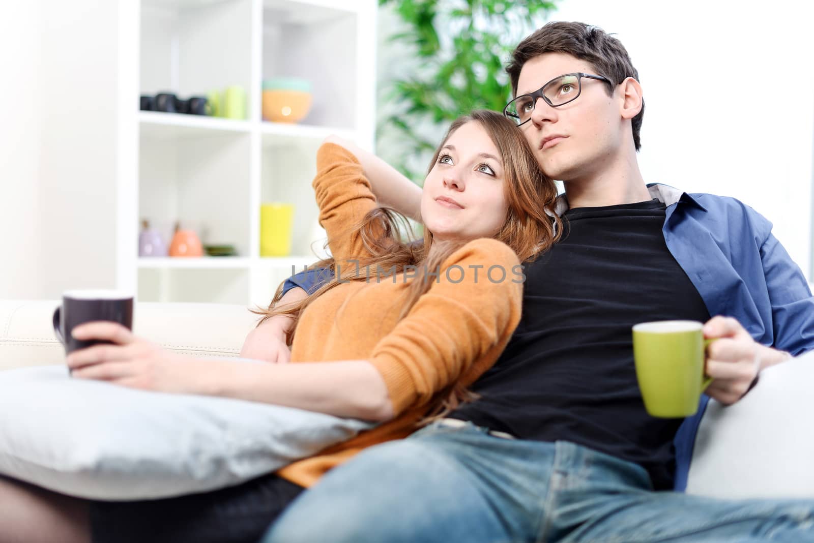 Lovely couple watching TV while drinking tea in their living room