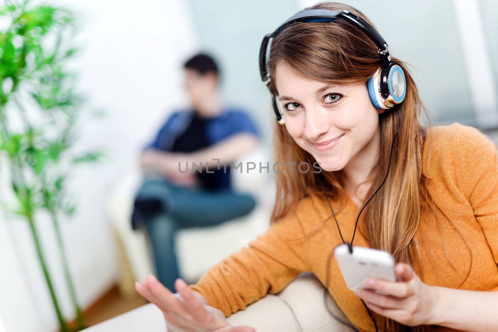 Beautiful blond listening to some music while her boyfriend is bored