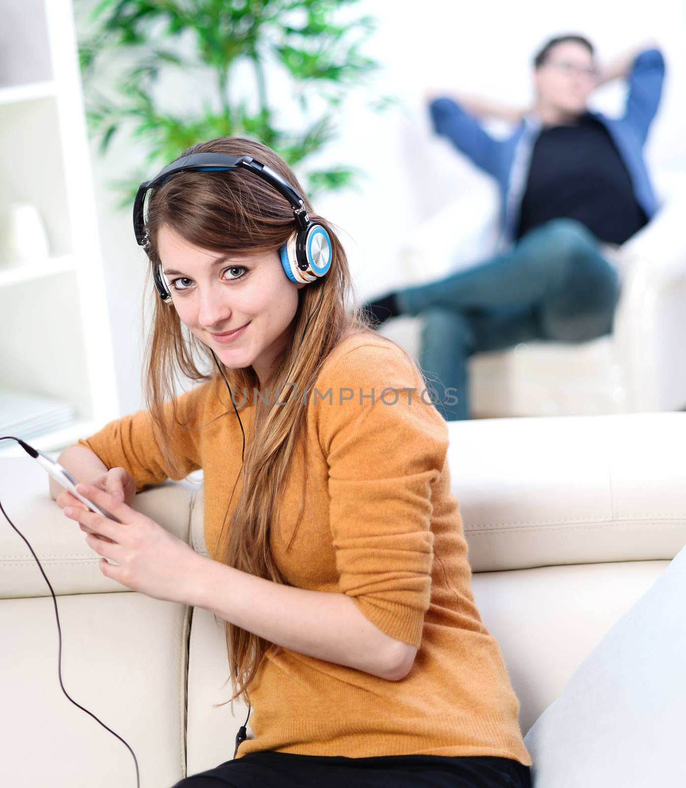 Beautiful blond listening to some music while her boyfriend is bored