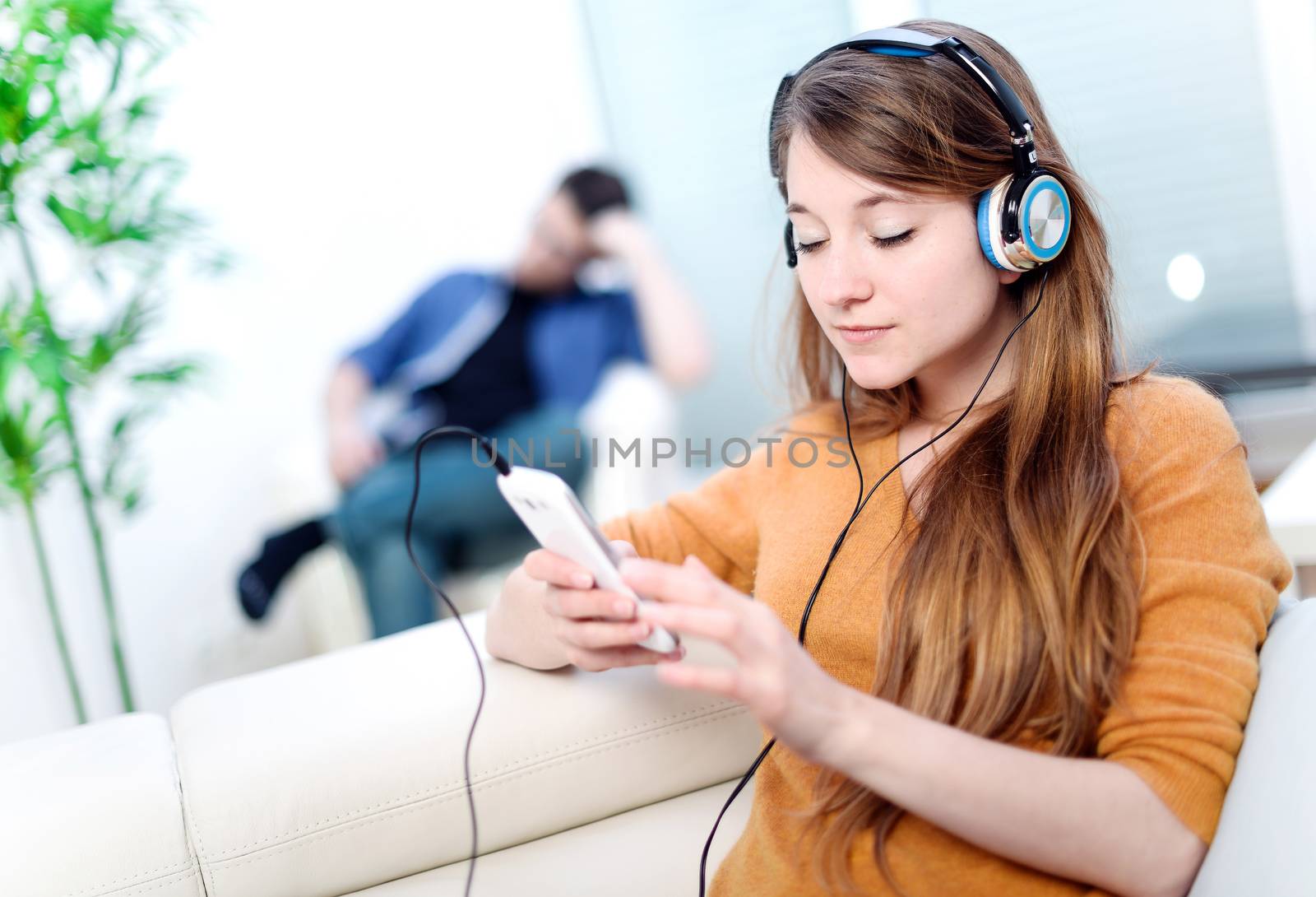 Beautiful blond listening to some music while her boyfriend is bored