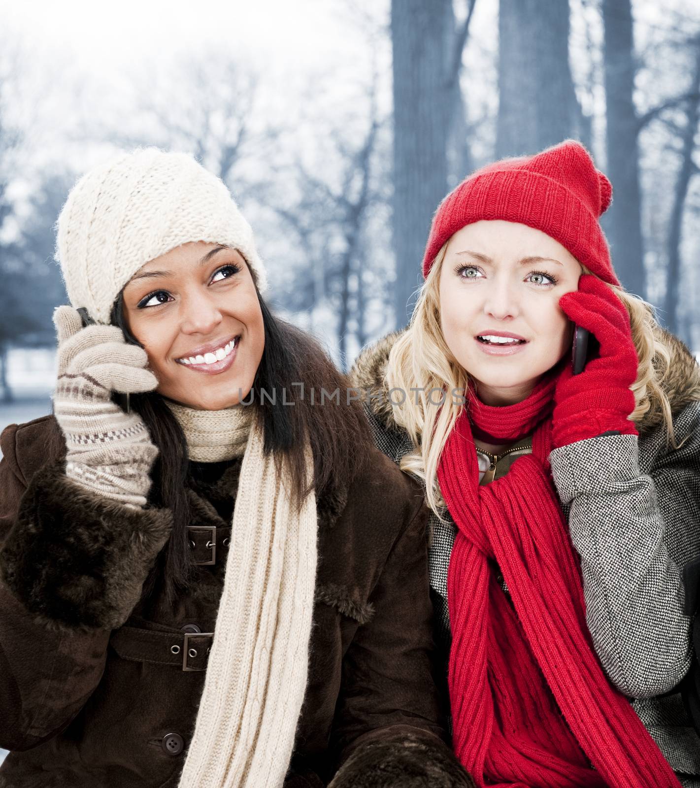 Portrait of two young female friends on the phone outdoors in winter