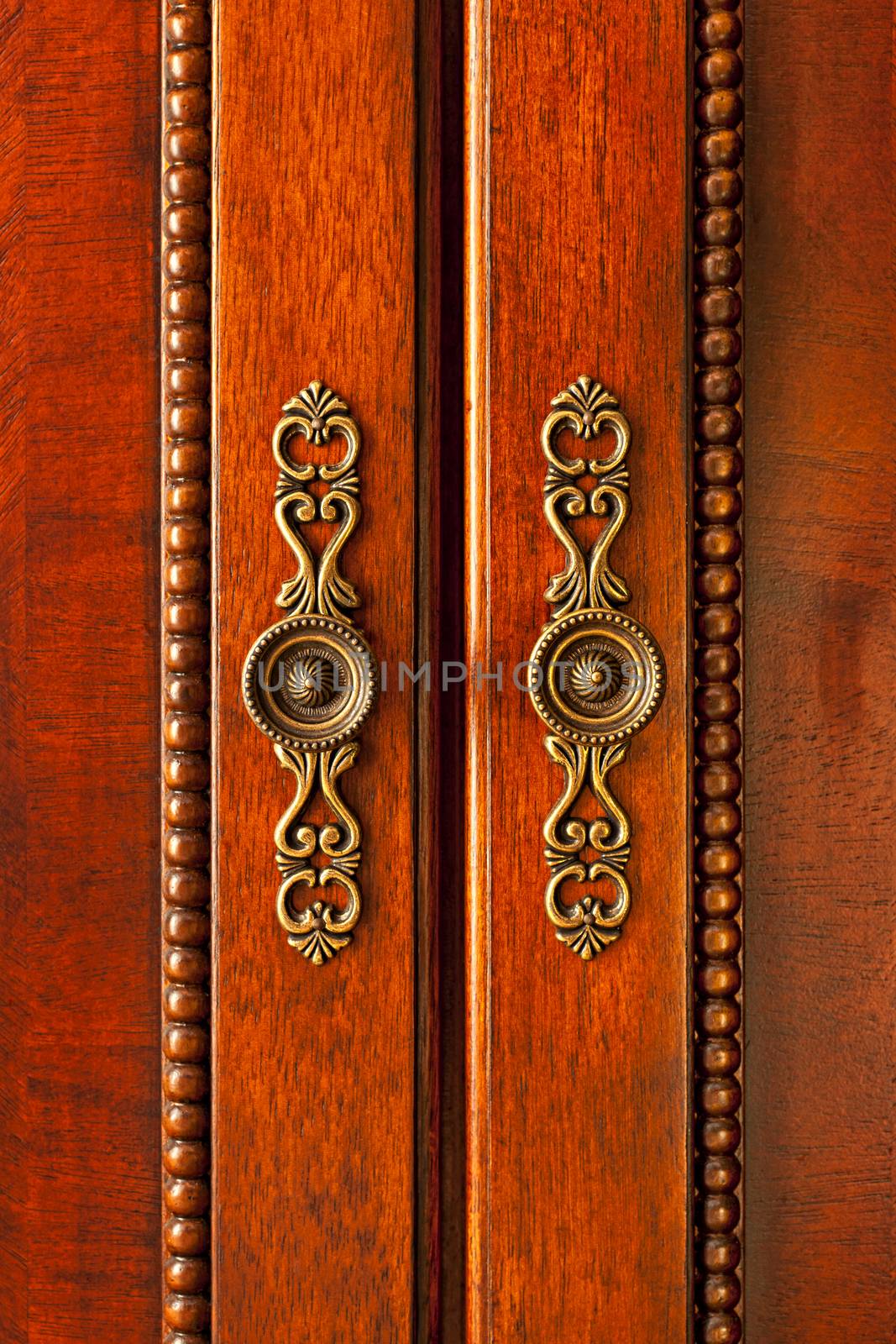 Ornate handles on wooden cabinet doors closeup