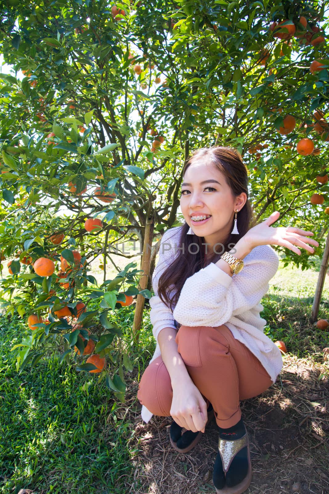 Pretty Asia woman in orange grove smiling by jakgree