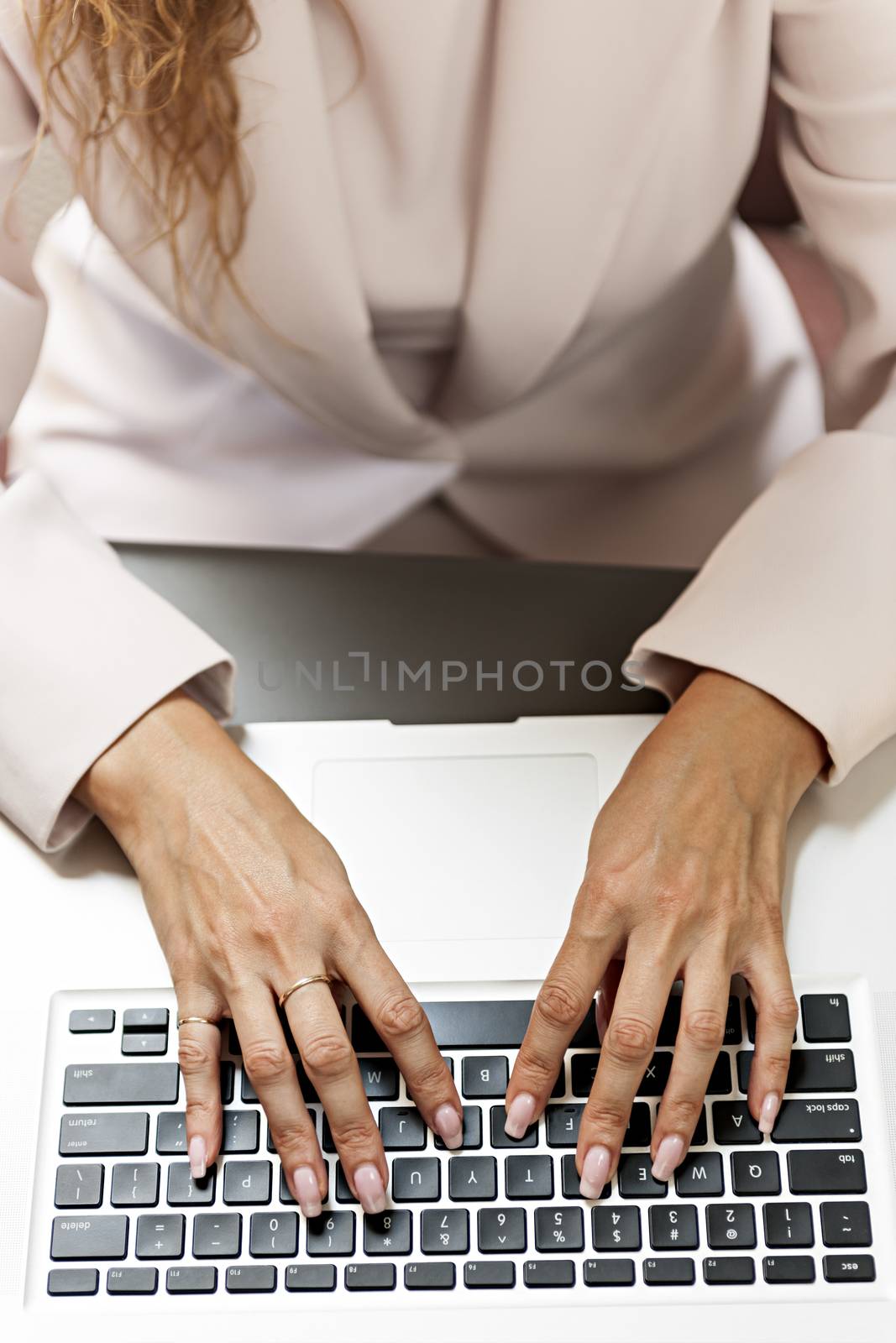Female hands typing on laptop keyboard from above