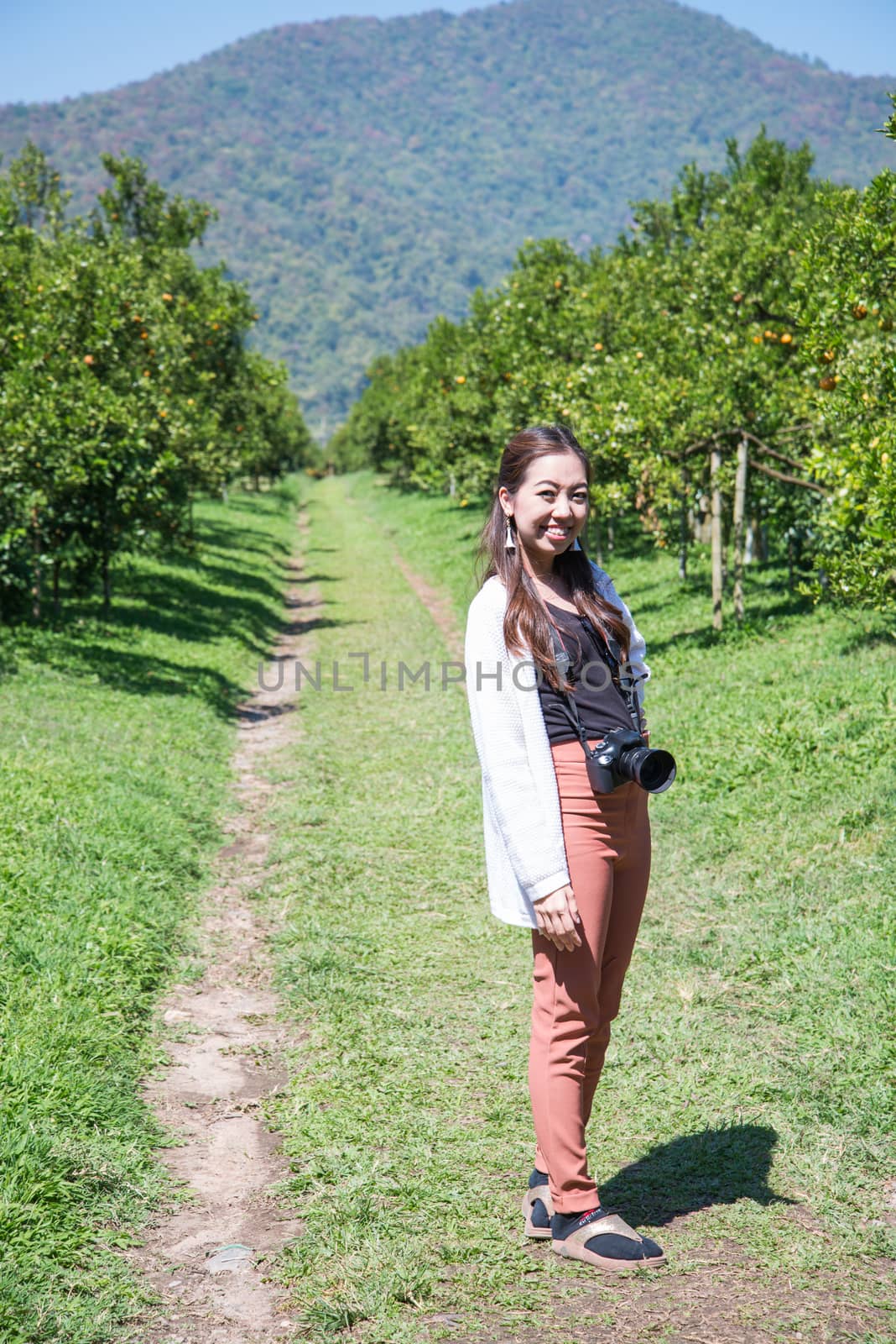 pretty Asia woman in orange farm smiling by jakgree