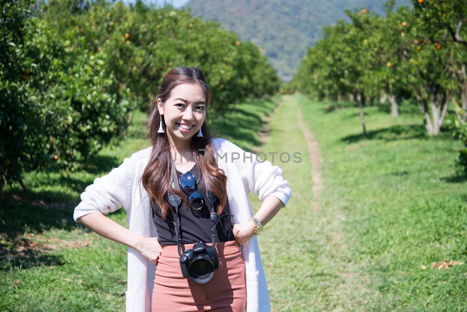 pretty Asia woman in orange farm smiling by jakgree