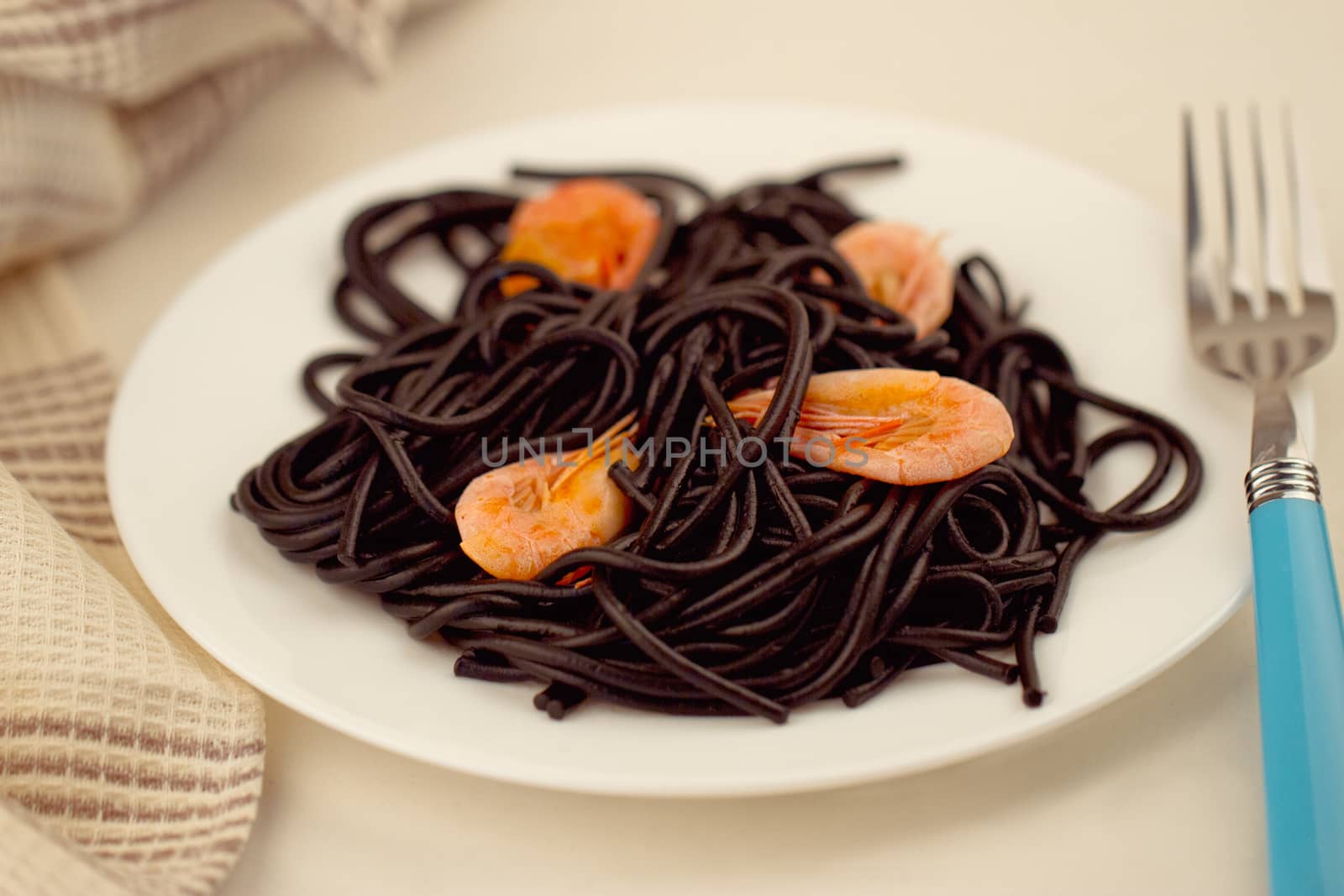 Black spaghetti with prawns on white plate