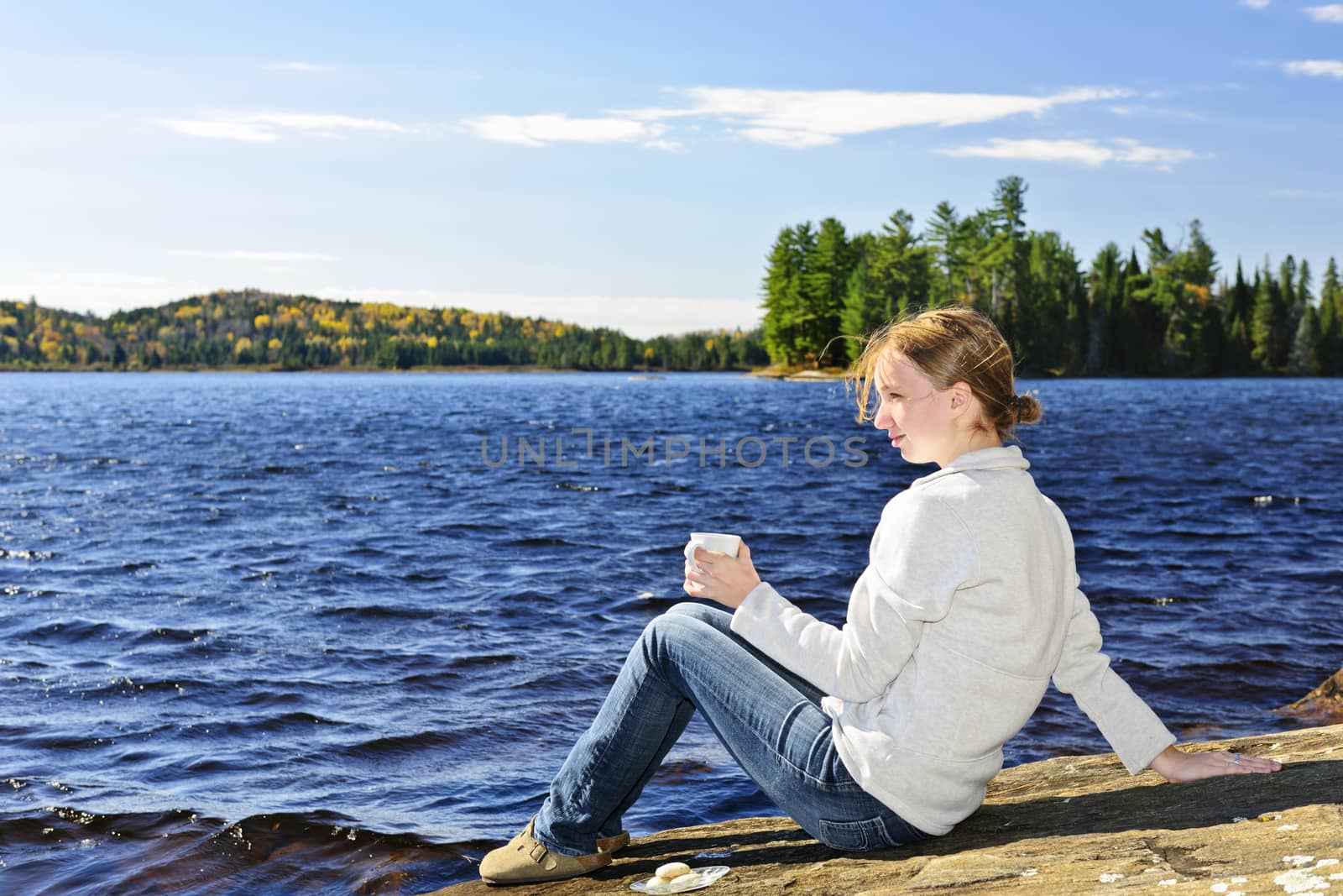 Young woman relaxing at lake shore by elenathewise