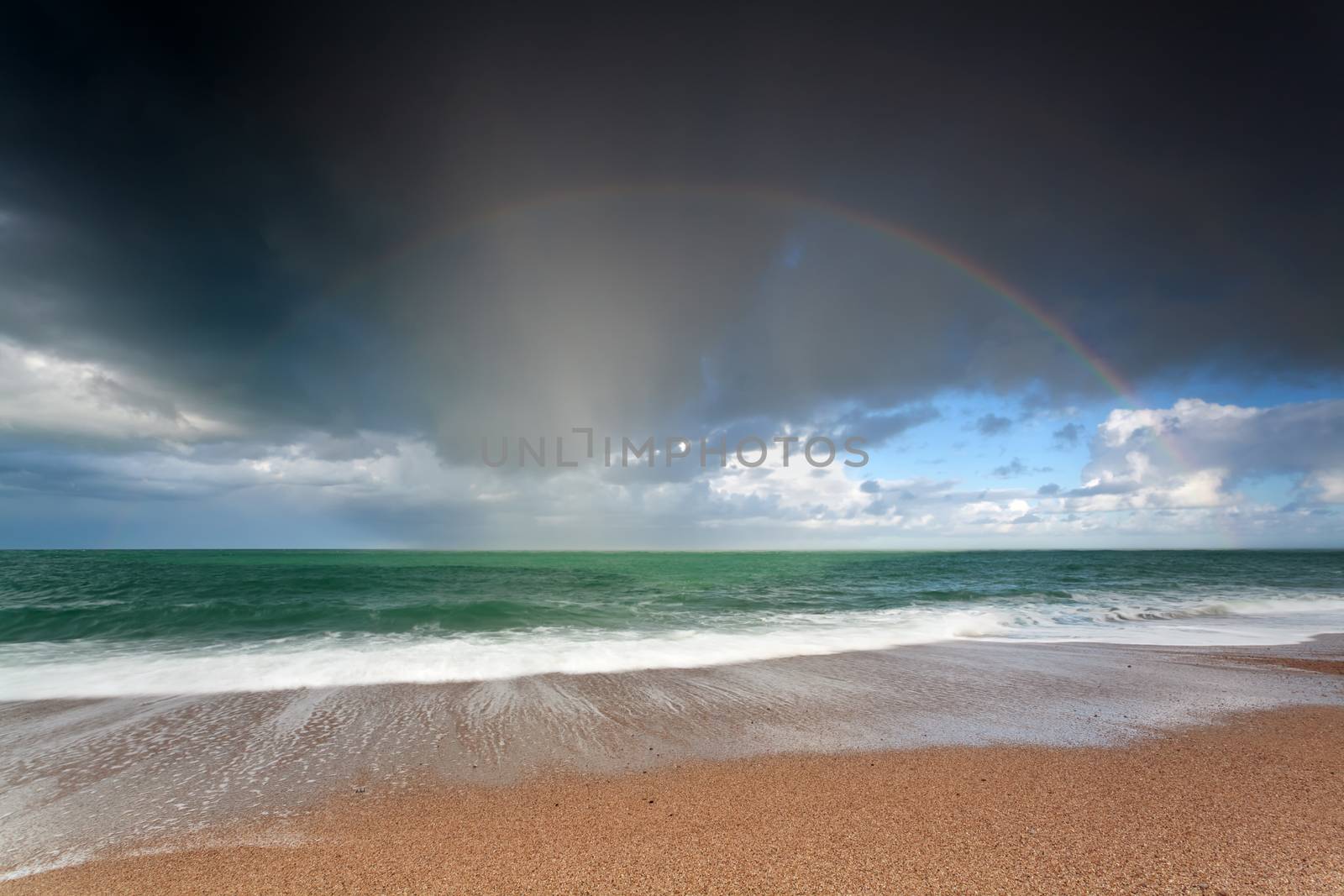 beautiful rainbow over ocean waves ob sand beach, France
