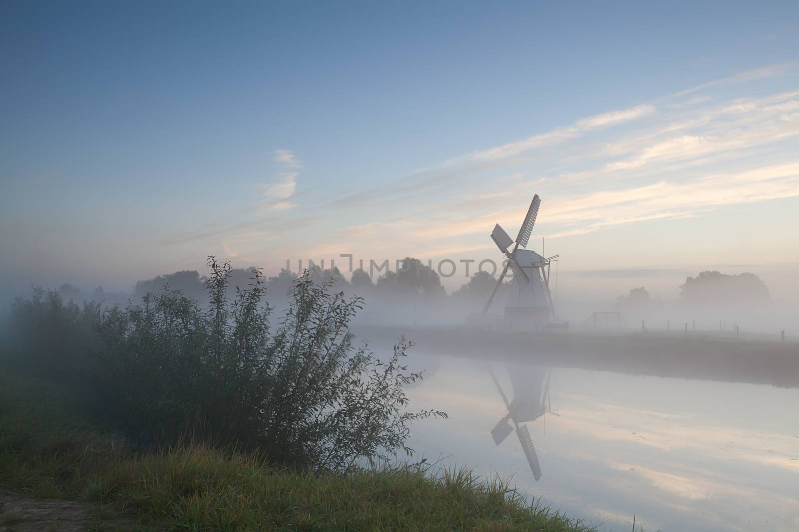 windmill by river in morning fog by catolla
