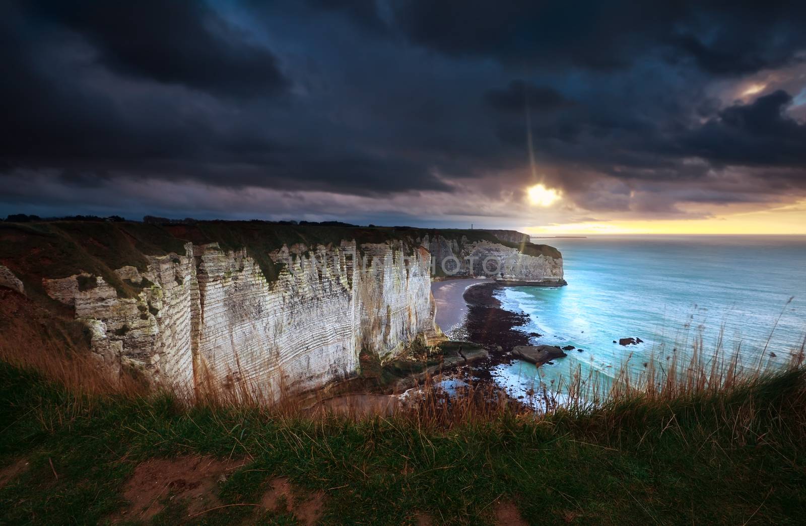 sunshine and storm sky over cliffs in ocean by catolla