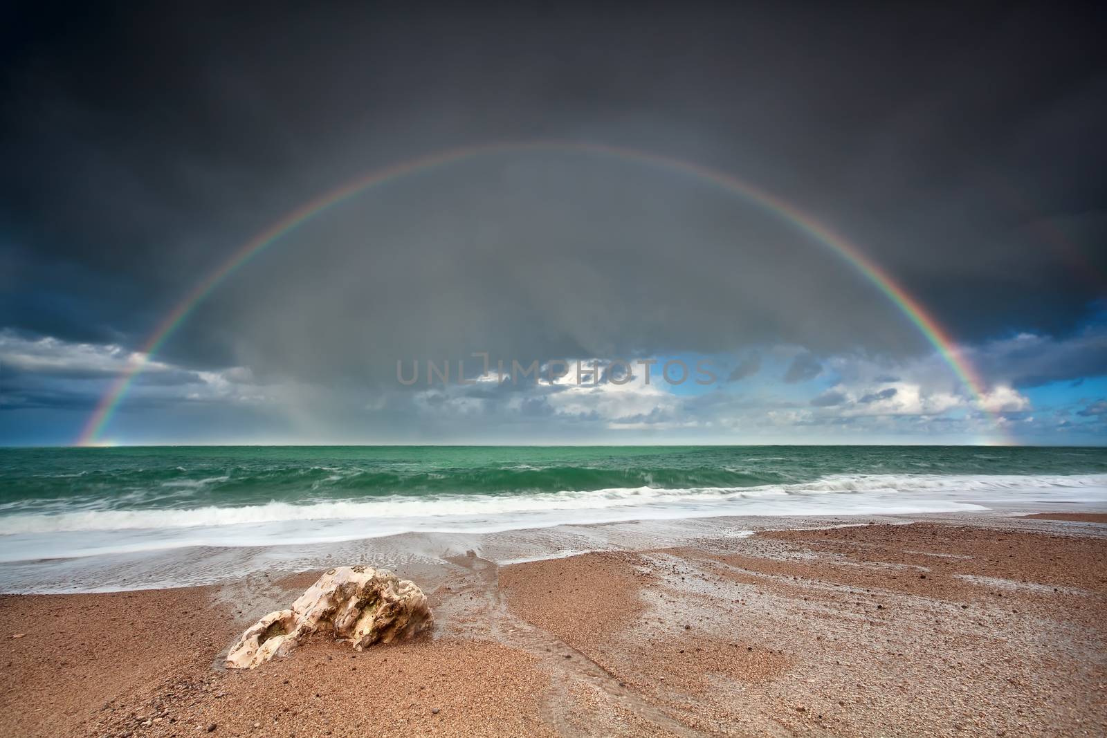 rainbow over stone beach in Atlantic ocean, Etretat, France