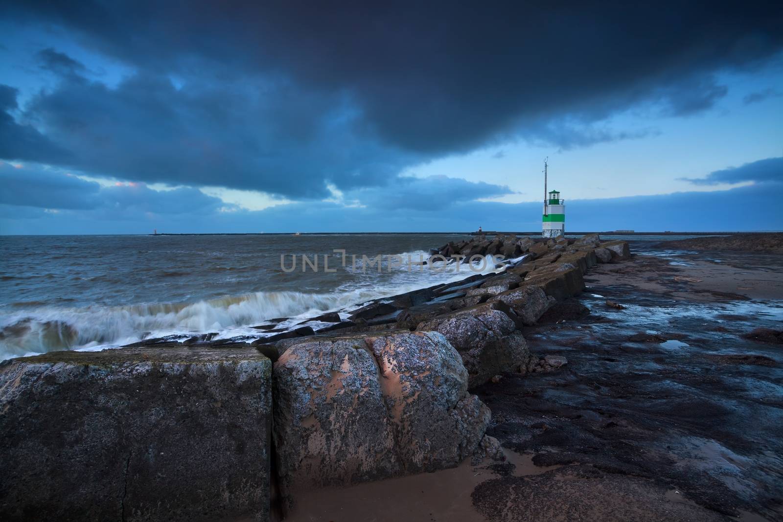 green lighthouse in dusk on North sea, Netherlands