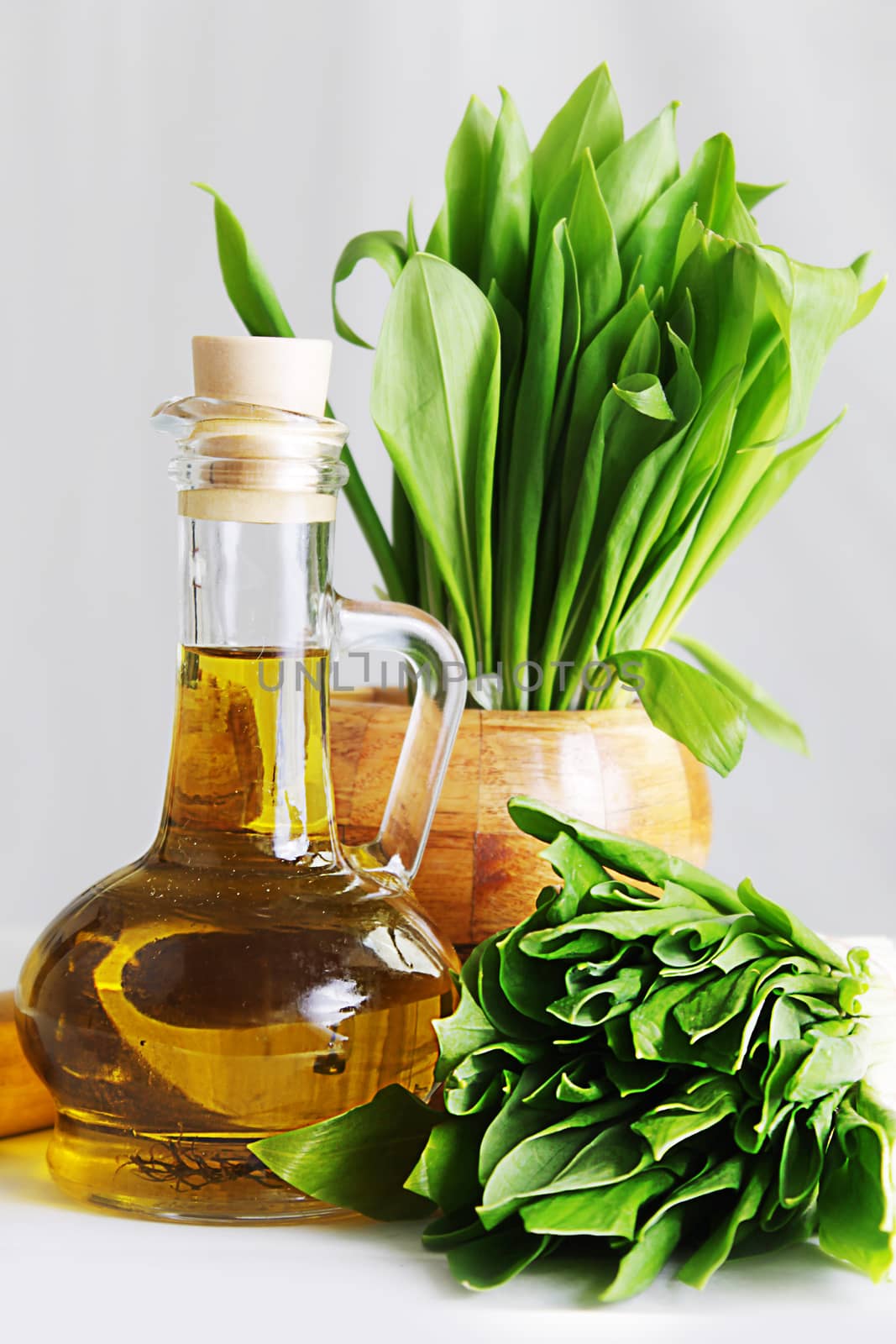 Cluster of fresh wild garlic leaves with mortar and oil