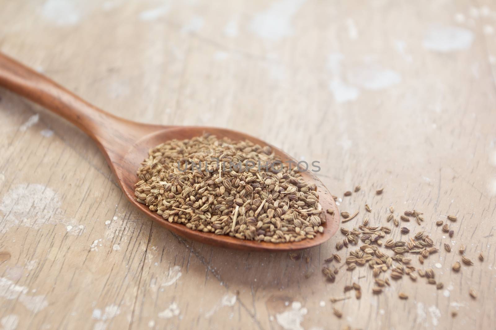 cumin seeds in wooden spoon on grung wood background