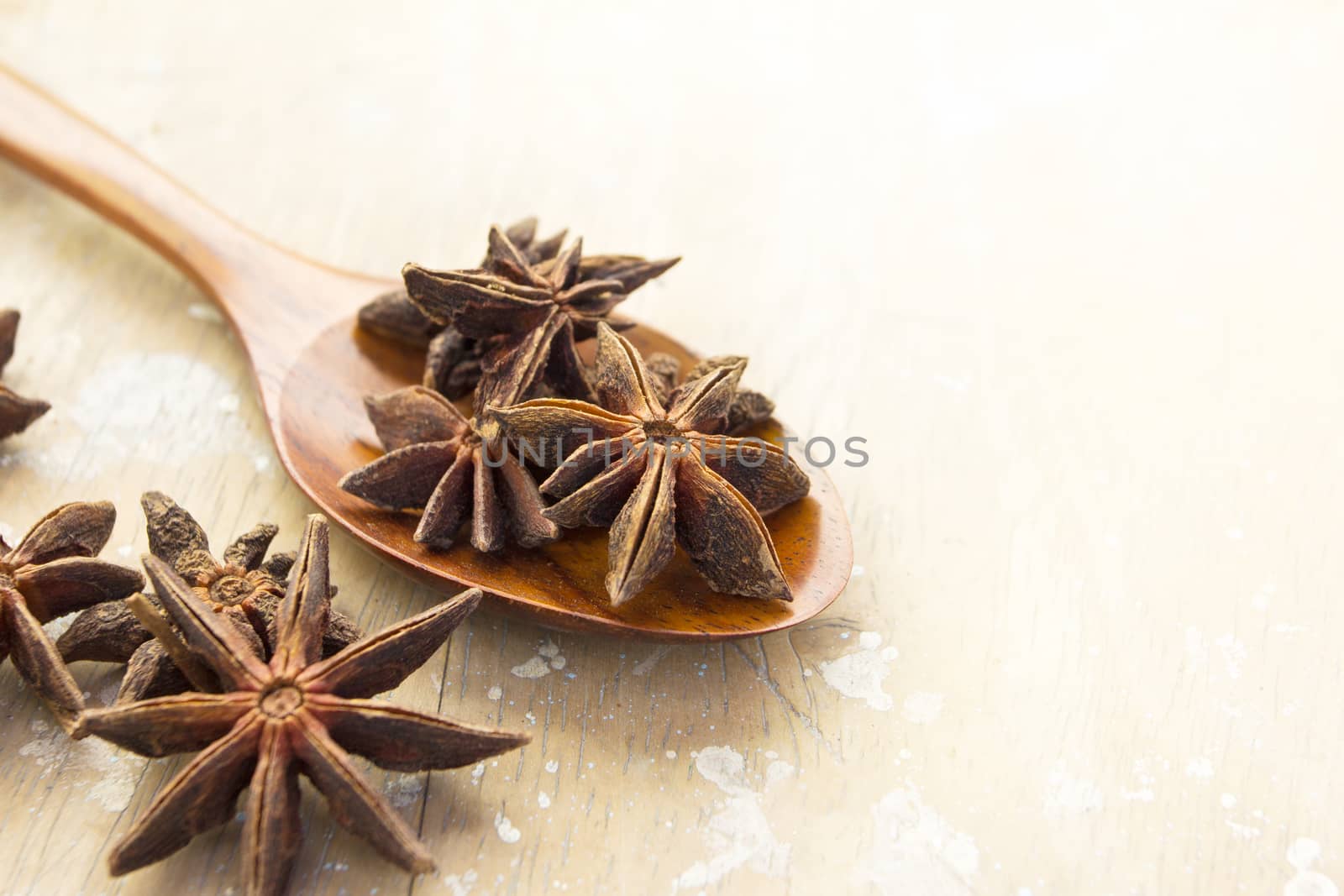 Anise stars in wood spoon and on the vintage wooden surface background