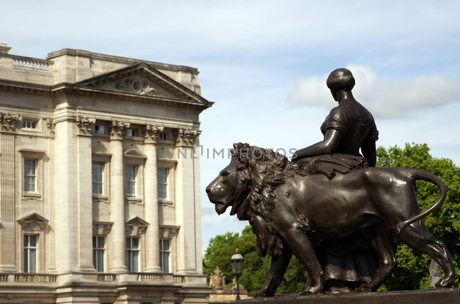 A bronze woman statue standing next to a lion statue
