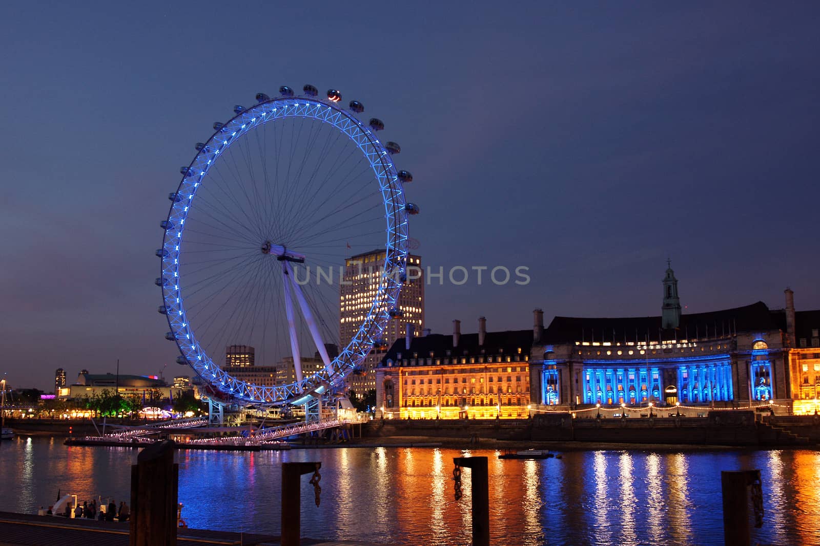 A large ferris wheel as seen from a bridge in London