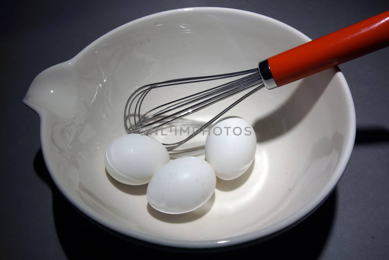 Three eggs in a mixing bowl with a wisk