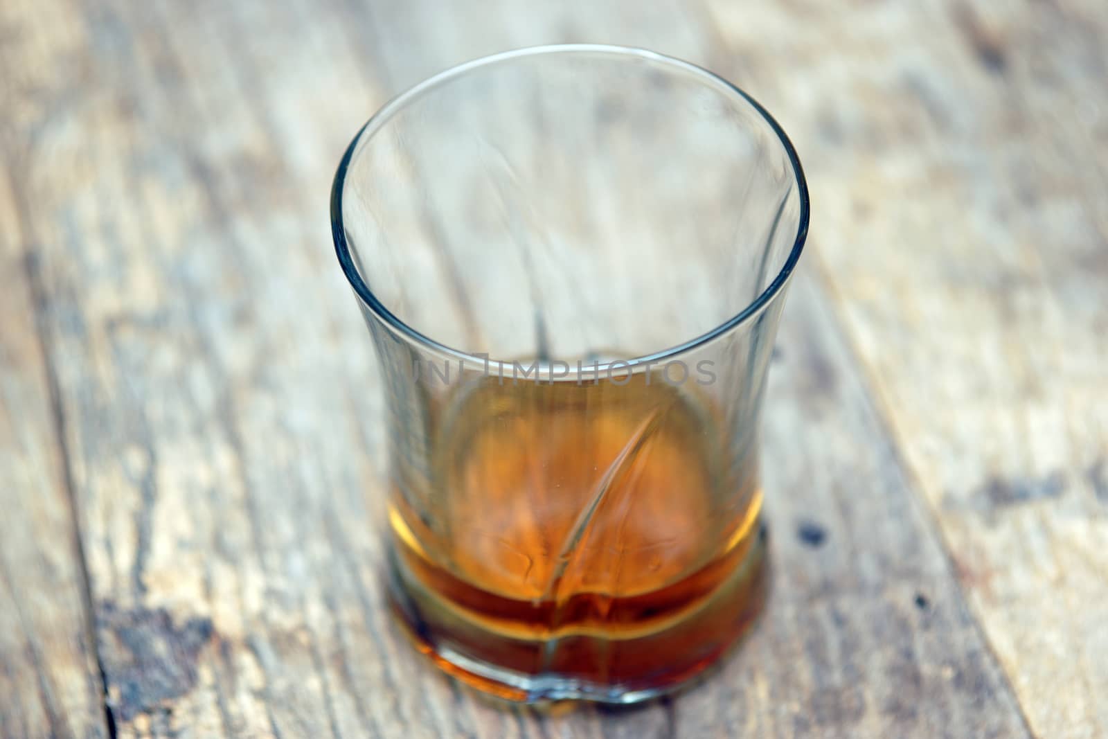 A single glass of scotch on a wooden table