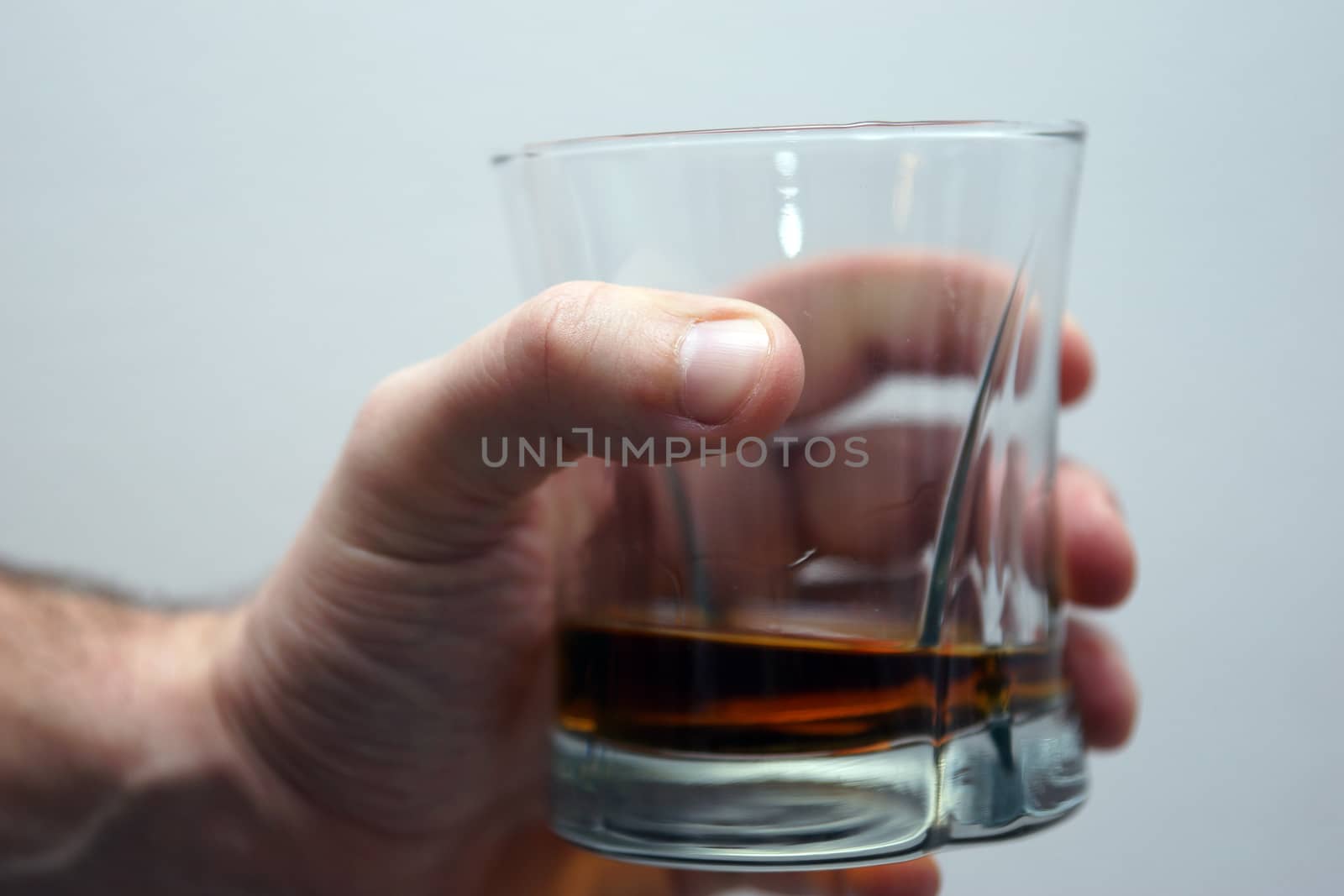 A glass of scotch being held by a man's hand