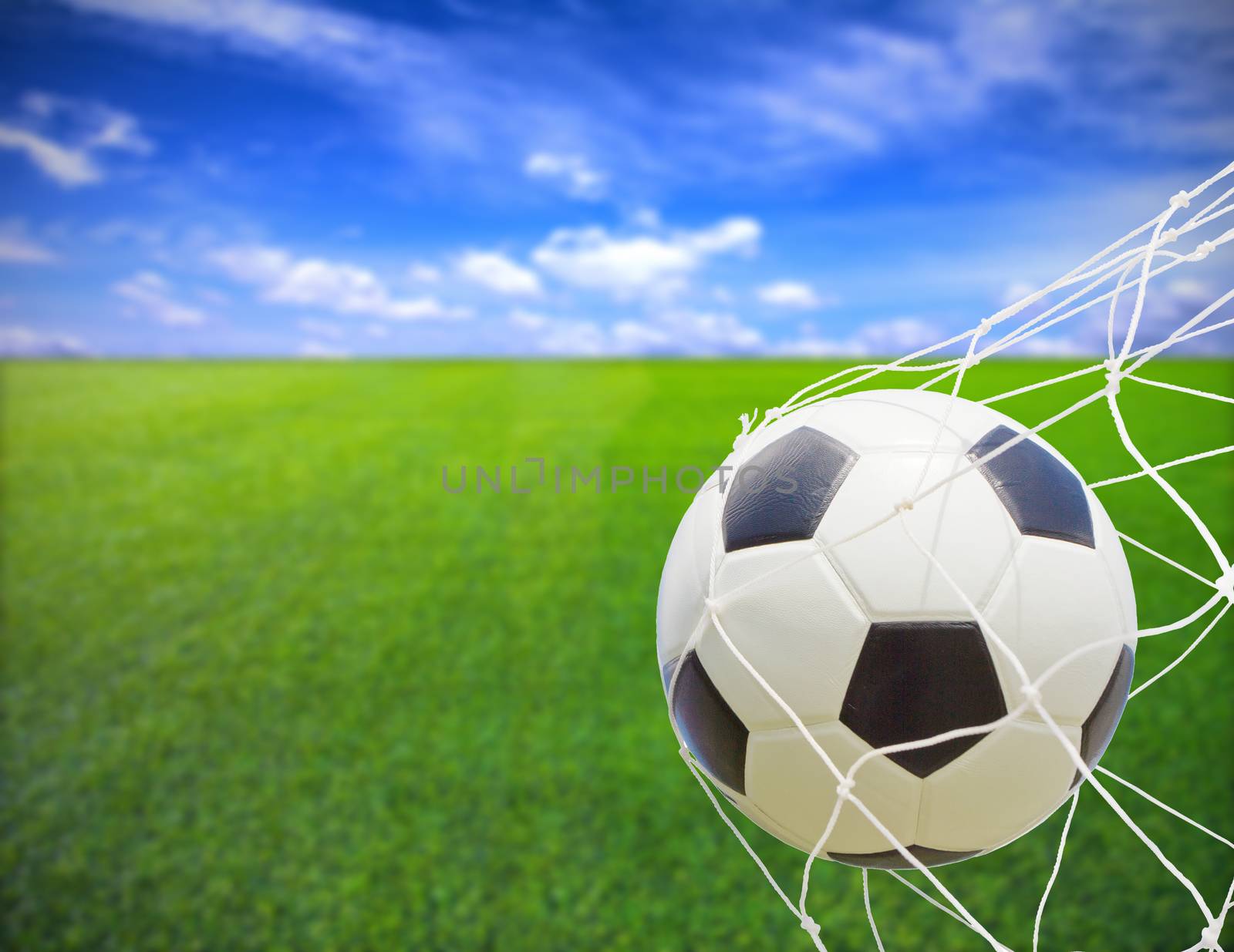 soccer ball in goal net over blue sky background 