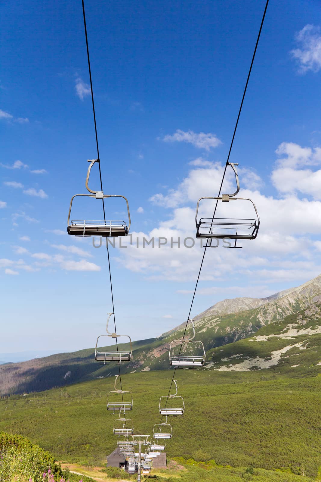 view on mountains in summer with ski lift on blue sky background