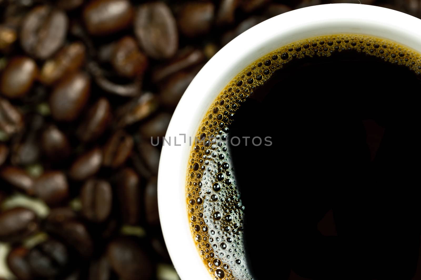 Closeup of hot coffee in white cup on coffe beans