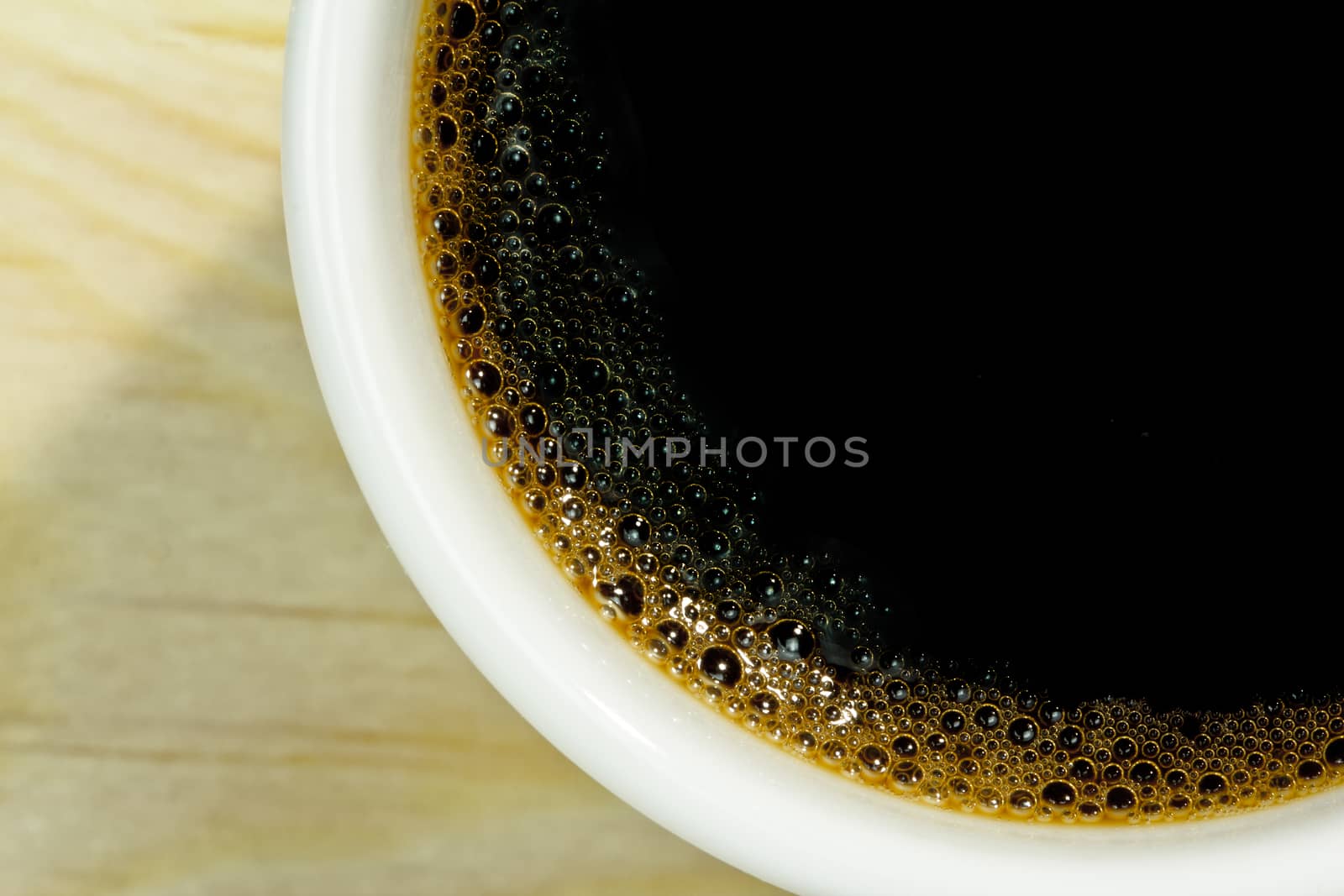 Close up coffee foam in white coffee cup on wood background