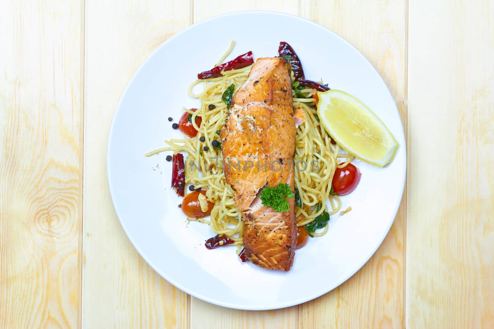 Spaghetti Salmon with chilli, tomato on white plate over wood background, View top