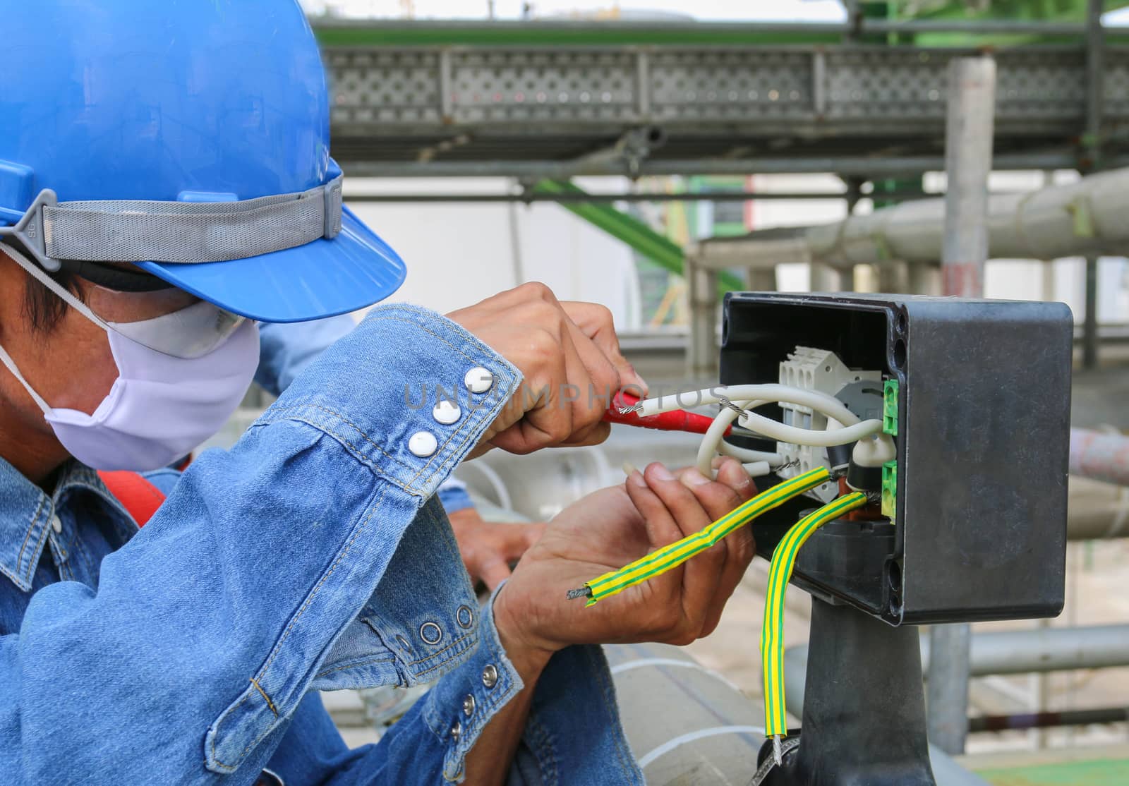 Technician use screwdriver tighten nut in junction box 