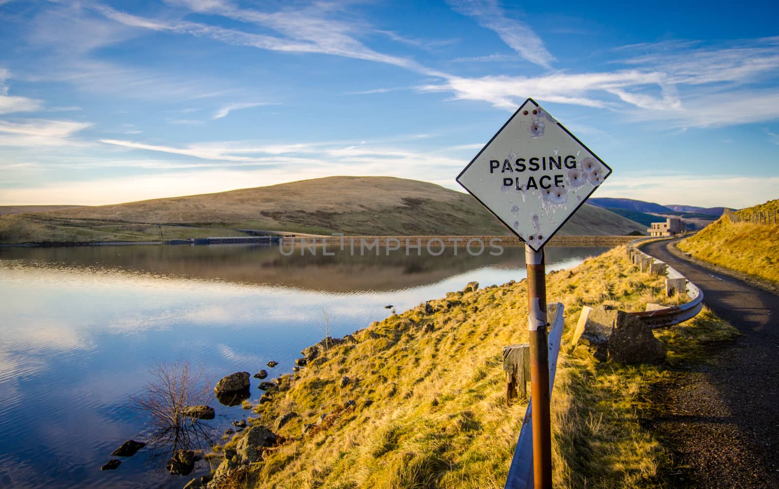 Passing Place Sign With Bullet Holes On Rural Road Beside A Lake In Scotland