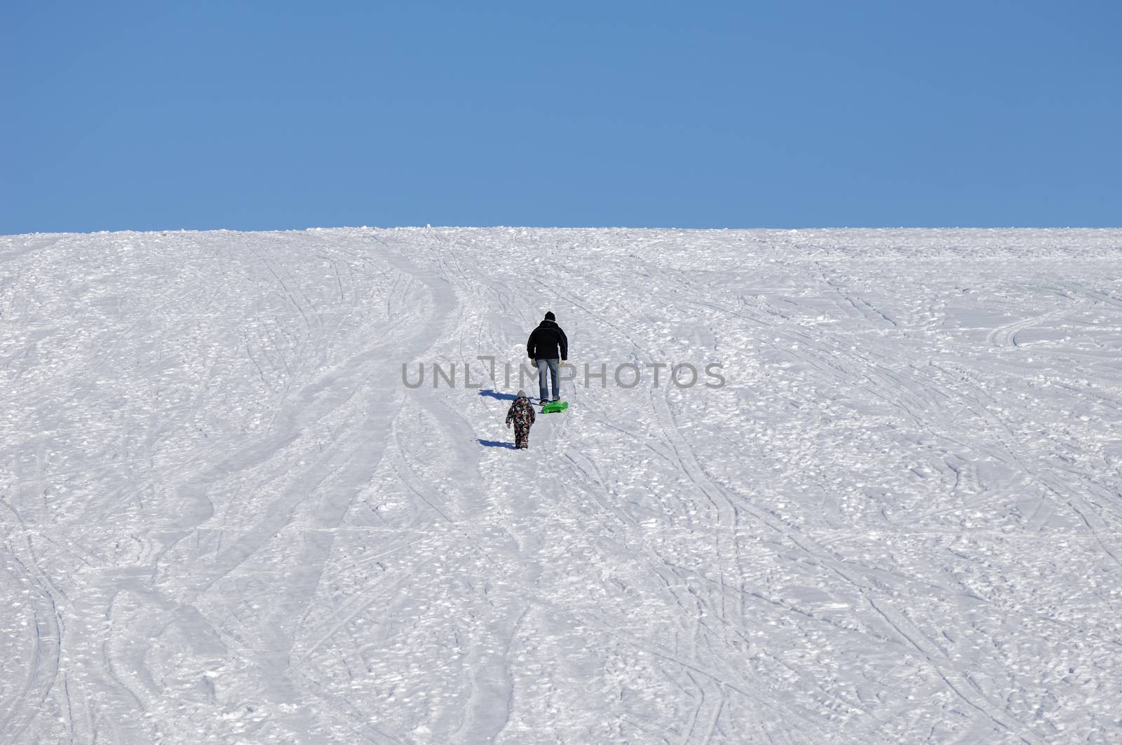 Two people are walking up the hill at winter