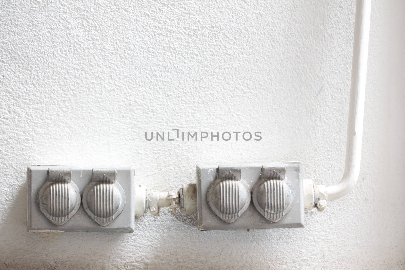 Old dirty electrical outlets on the white wall 