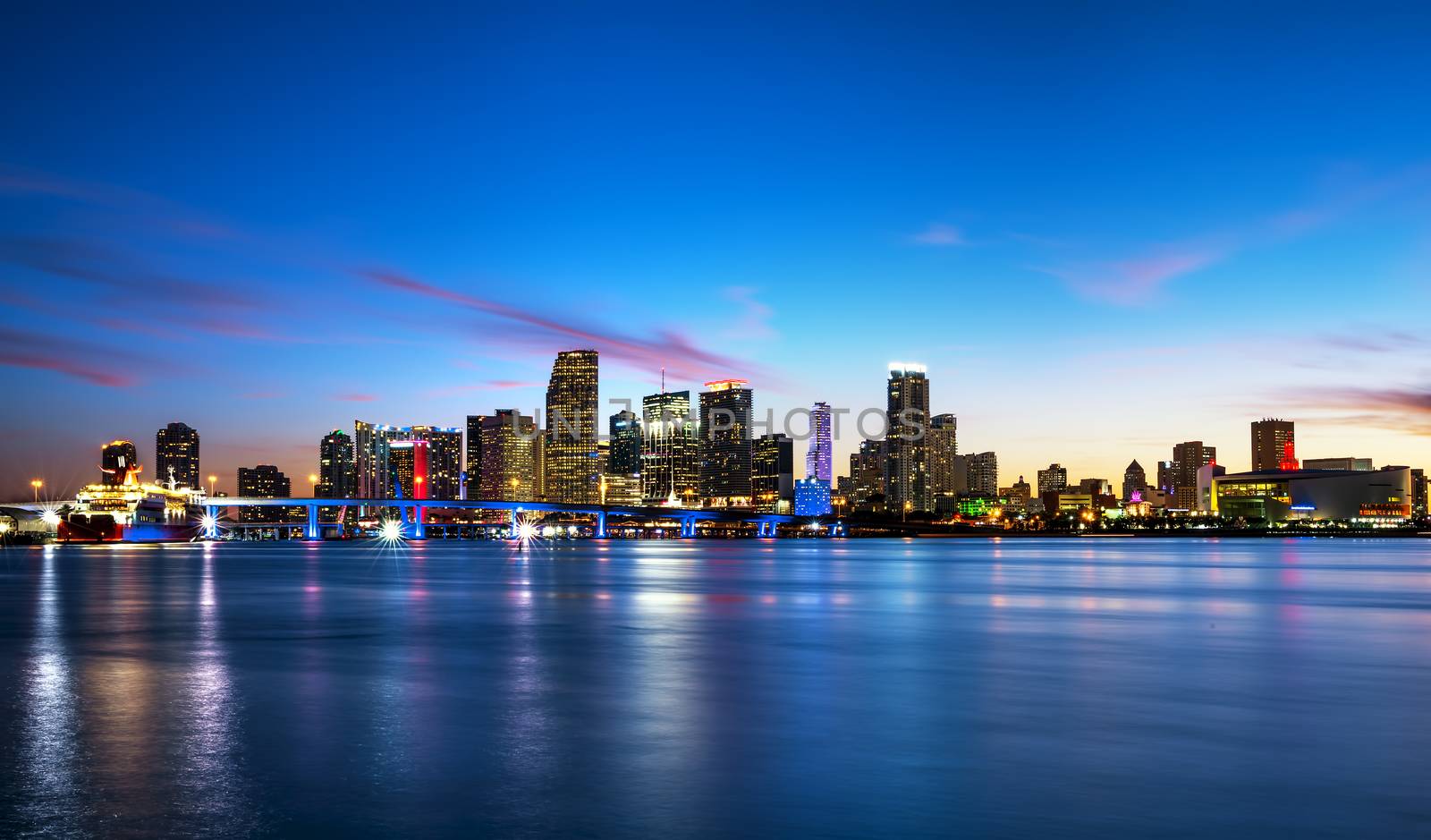 Miami city skyline panorama at dusk with urban skyscrapers over sea with reflection 