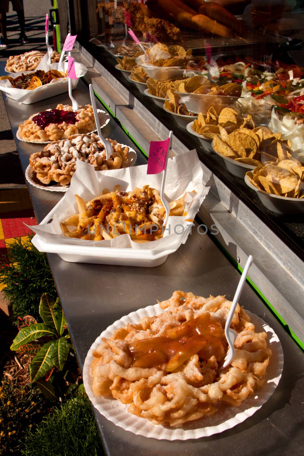 Several funnel cakes are displayed for sale outside a food vendor's booth at a county fair.