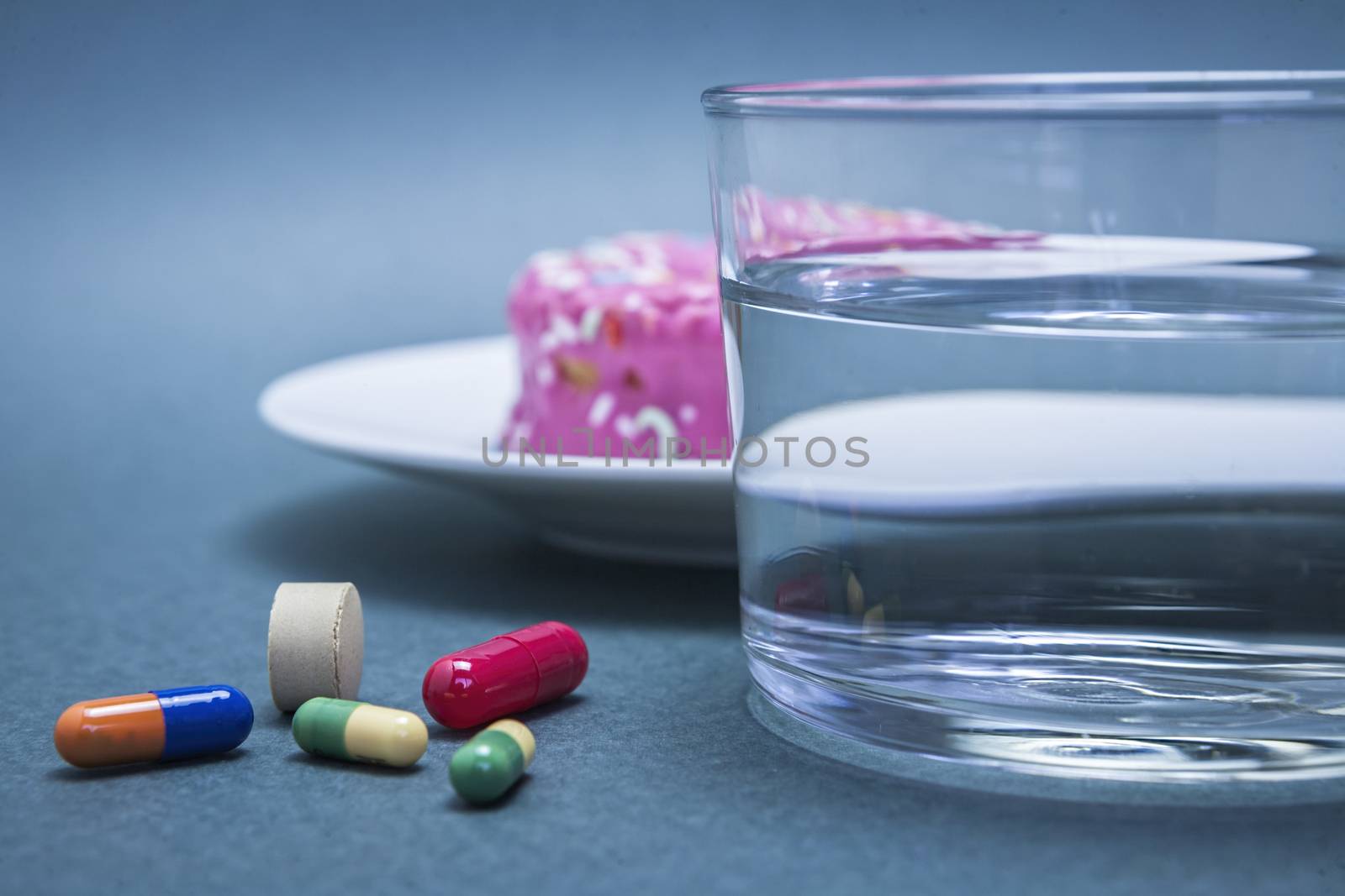 Various medicines to combat diabetes along with a sweet cake and glass water, concept of disease of hyperglycemia or diabetes