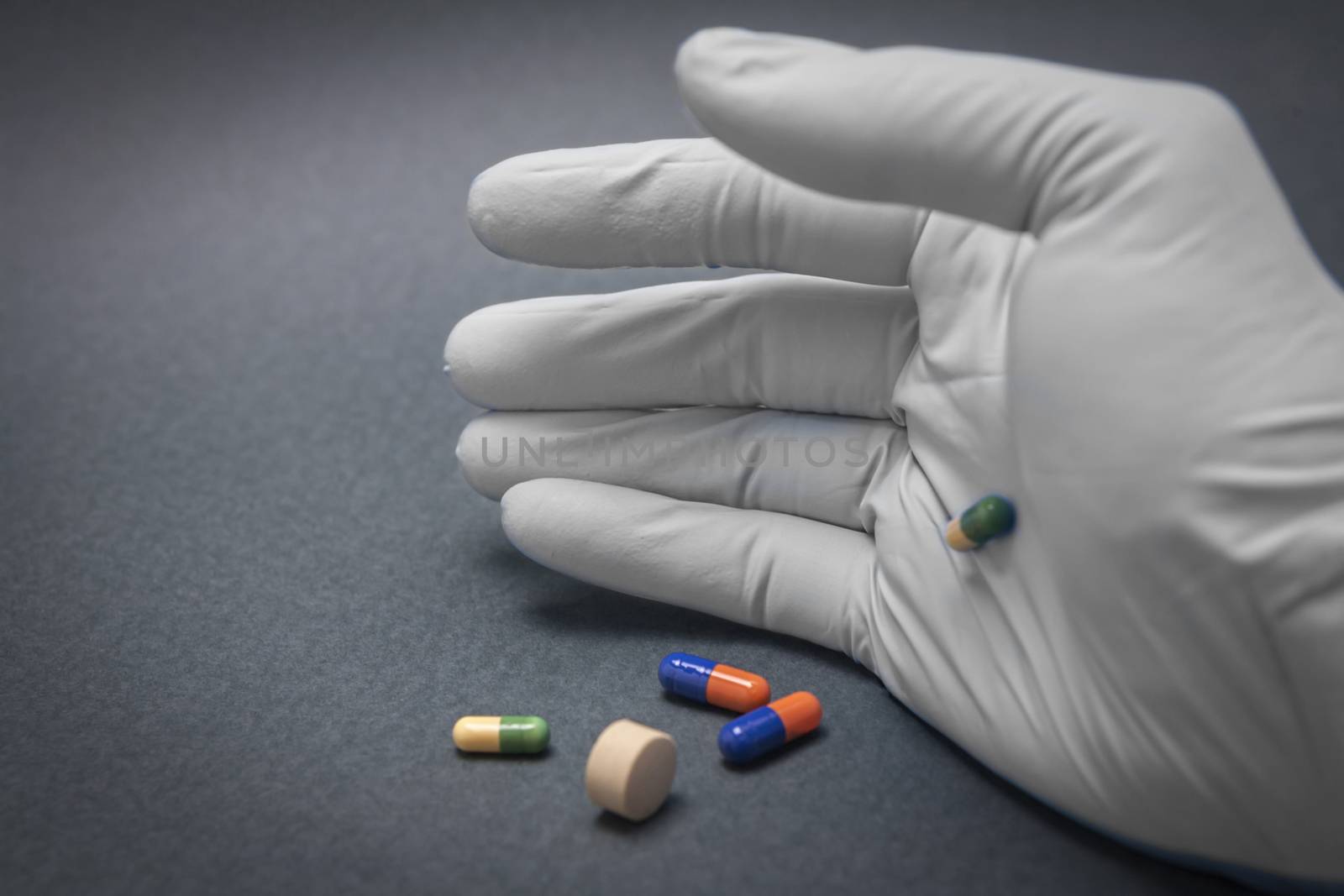 Hand with blue white glove turning various pills
